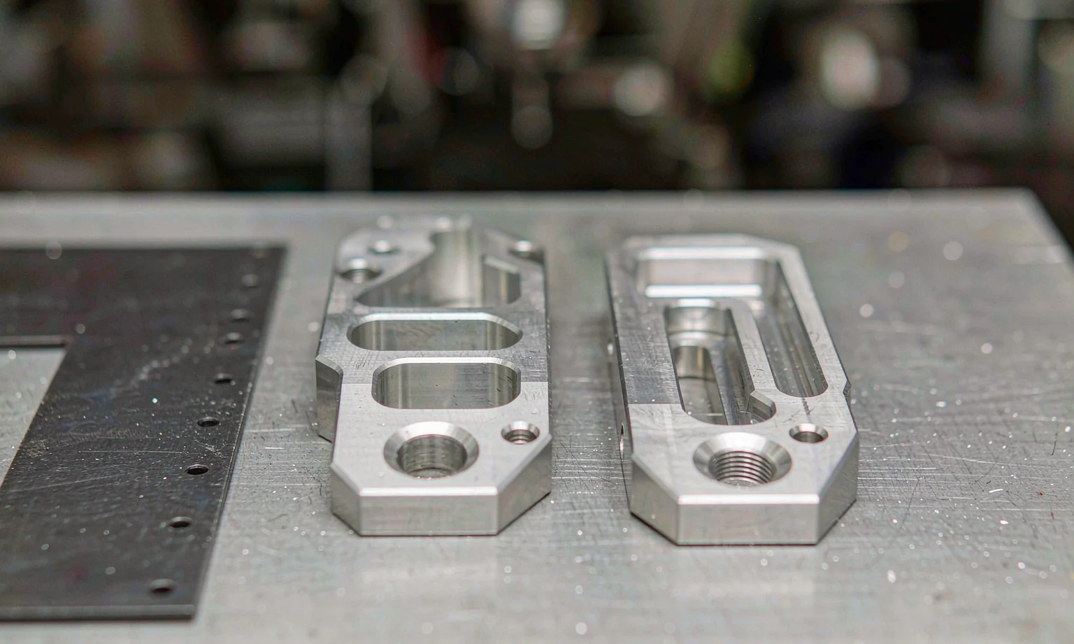CNC milled aluminium parts beside a laser-cut steel plate