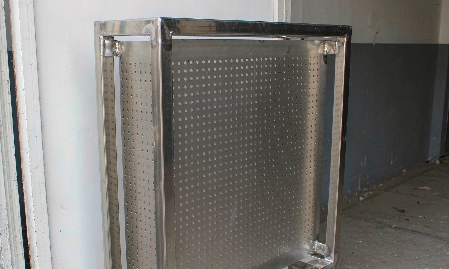 Perforated stainless steel guard panel in a welded frame